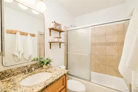 a bathroom with a granite countertop sink toilet and shower