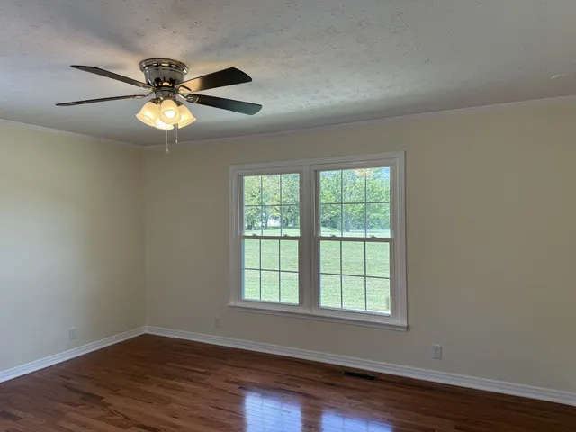 a view of an empty room with wooden floor and a window