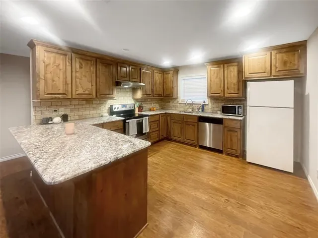 a kitchen with stainless steel appliances granite countertop a sink stove refrigerator and cabinets
