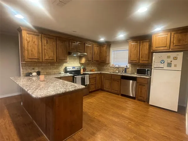 a kitchen with stainless steel appliances granite countertop a sink stove refrigerator and cabinets