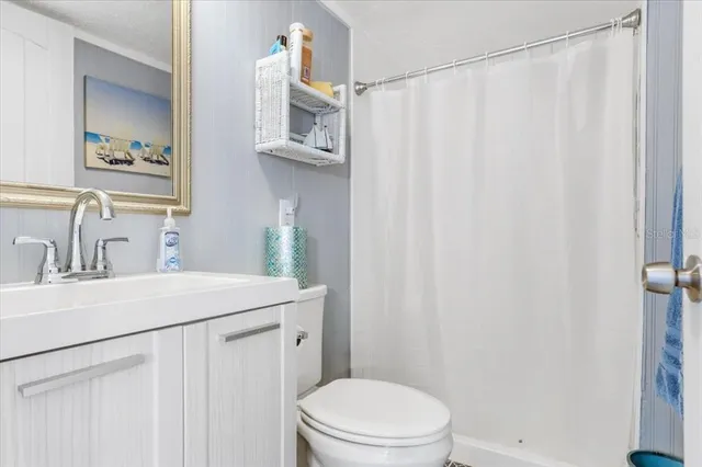 a bathroom with a sink a toilet a mirror and shower curtain