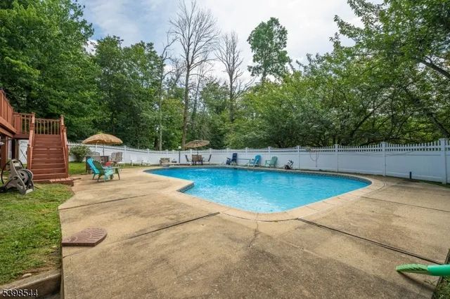 a view of a swimming pool with a bench and trees around