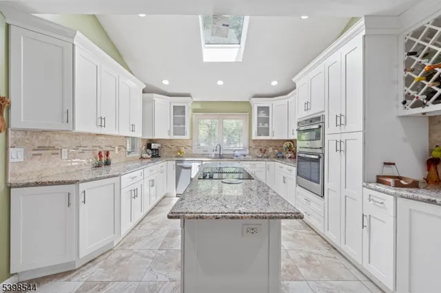 a large kitchen with granite countertop lots of counter space a sink appliances and cabinets