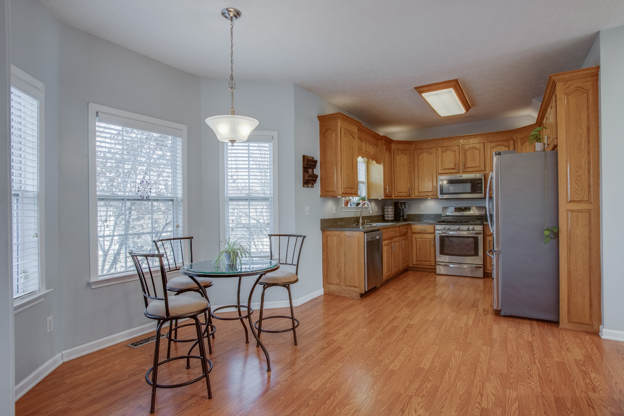2918 Buckner Lane Spring Hill, TN 37174 - Photo 13 of 54 a kitchen with stainless steel appliances a stove a sink dishwasher a refrigerator and a dining table with wooden floor