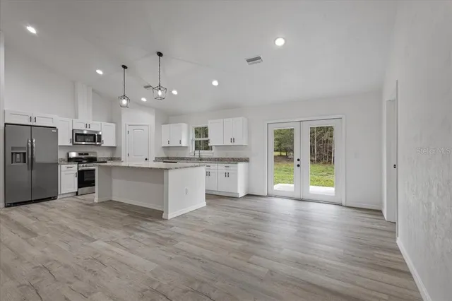 a kitchen with stainless steel appliances granite countertop a sink a stove a refrigerator and cabinets