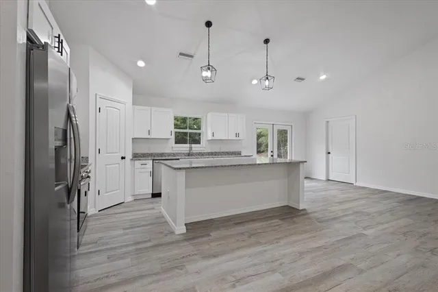 a large kitchen with granite countertop a sink a counter top space stainless steel appliances and cabinets