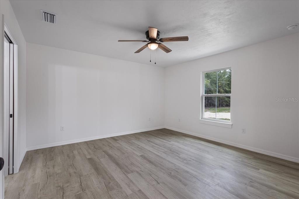 4899 Northwest 36th Street Bell, FL 32619 - Photo 19 of 67 an empty room with wooden floor ceiling fan and windows