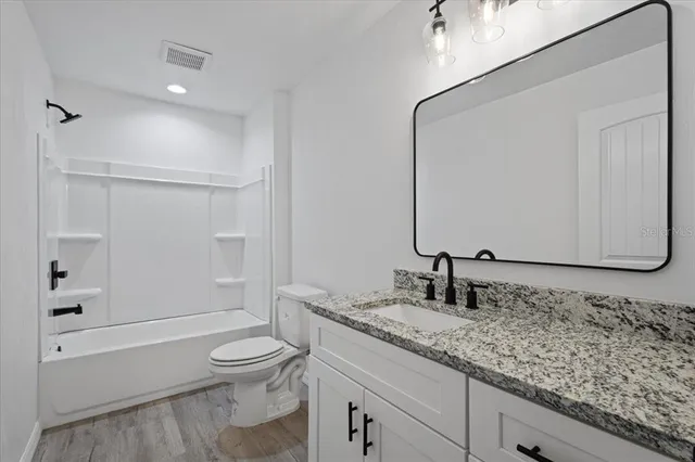 a view of an empty room with wooden floor and a ceiling fan