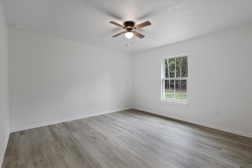 4899 Northwest 36th Street Bell, FL 32619 - Photo 25 of 67 an empty room with wooden floor chandelier fan and windows