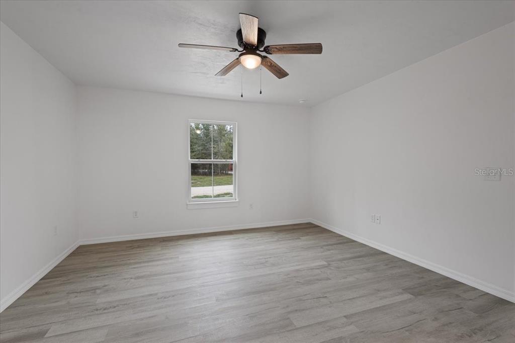 4899 Northwest 36th Street Bell, FL 32619 - Photo 27 of 67 an empty room with wooden floor chandelier fan and windows