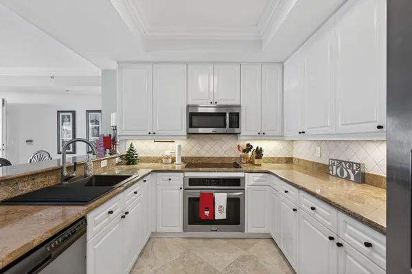 a kitchen with granite countertop white cabinets and stainless steel appliances
