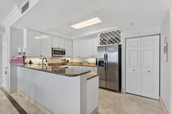 a kitchen with stainless steel appliances granite countertop a refrigerator a sink dishwasher a stove with white cabinets and refrigerator