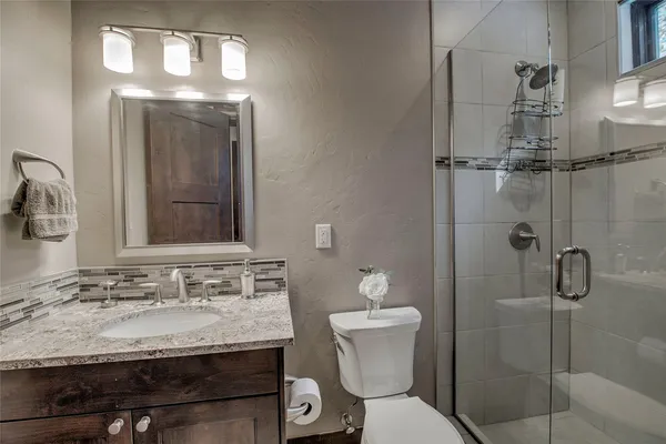 a bathroom with a granite countertop sink toilet a mirror and shower