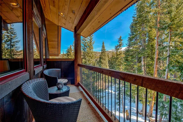 a balcony with wooden floor table and chairs
