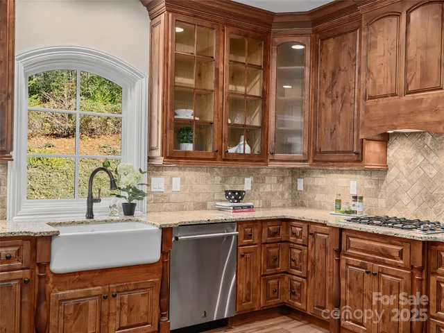 a kitchen with stainless steel appliances granite countertop a sink a stove and a wooden cabinets