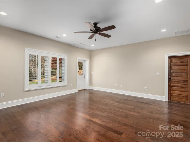 a view of an empty room with a window and wooden floor