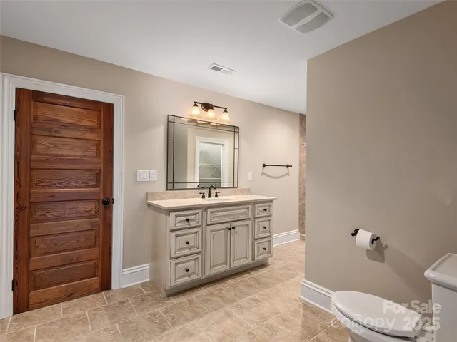 a spacious bathroom with a granite countertop toilet a sink and a mirror
