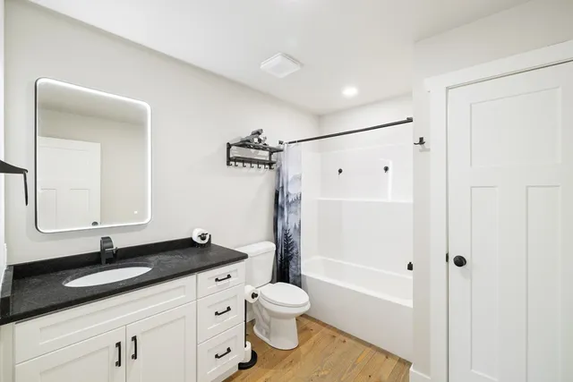 a bathroom with a granite countertop sink toilet a shower and a mirror