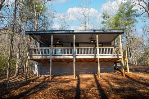 a view of house with wooden deck and backyard