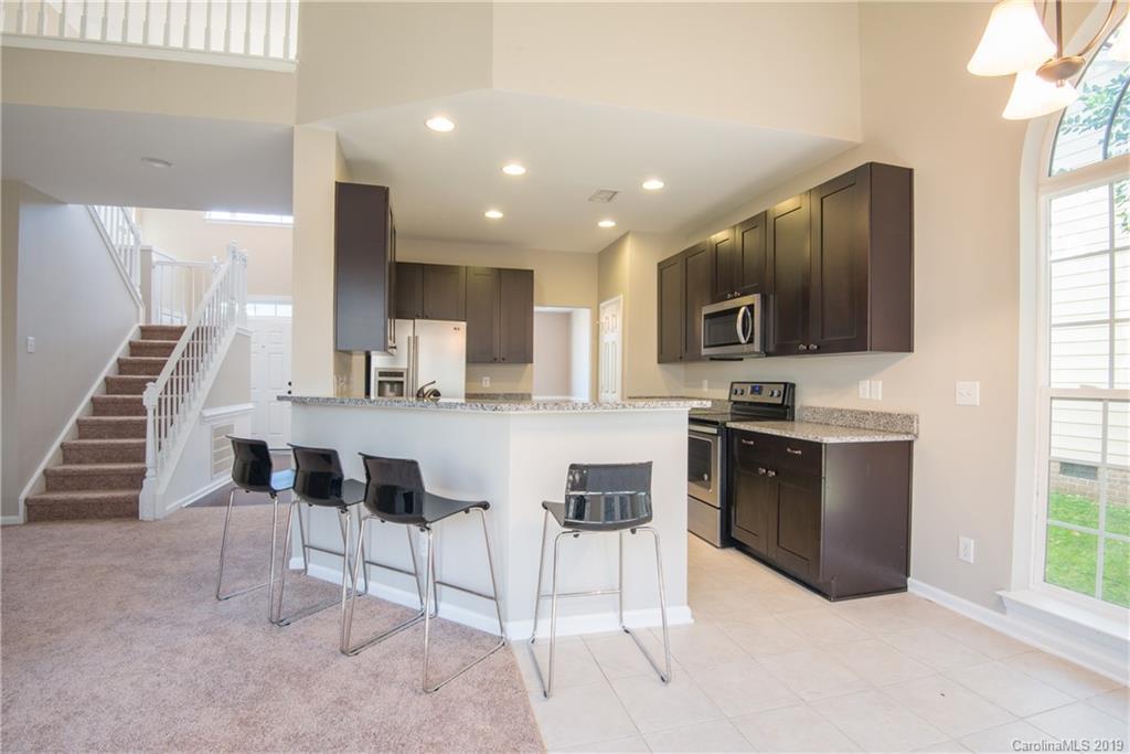 11712 Kennon Ridge Lane Huntersville, NC 28078 - Photo 5 of 31 a kitchen with kitchen island granite countertop wooden cabinets and stainless steel appliances