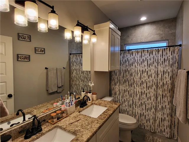 an empty room with wooden floor chandelier fan and windows