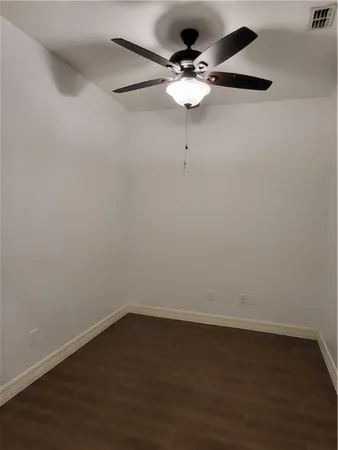 a view of an empty room with wooden floor and window