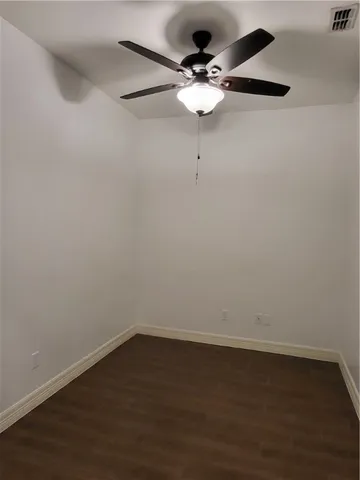 a view of an empty room with wooden floor and window