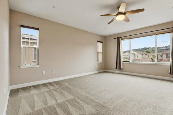 an empty room with windows and ceiling fan