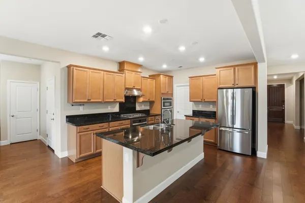 a large kitchen with stainless steel appliances granite countertop a stove a sink and a microwave