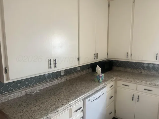 a kitchen with granite countertop white cabinets and a sink