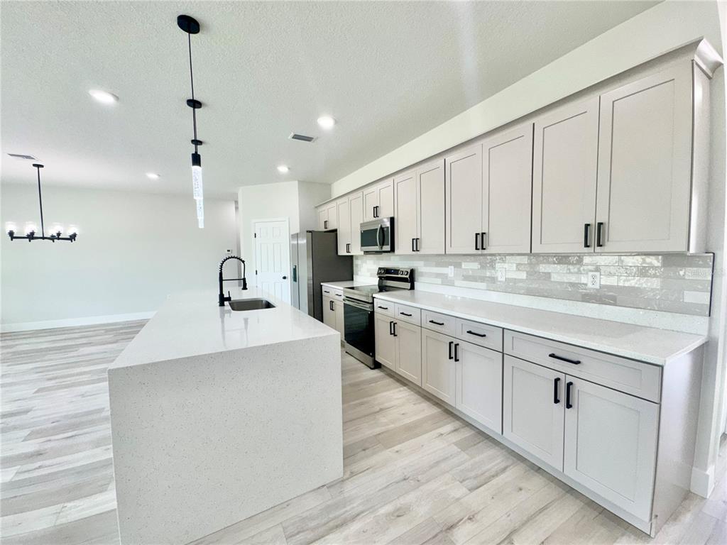 1690 Hamilton Avenue Southwest Palm Bay, FL 32908 - Photo 16 of 56 a large kitchen with kitchen island a sink a center island stainless steel appliances and a cabinets