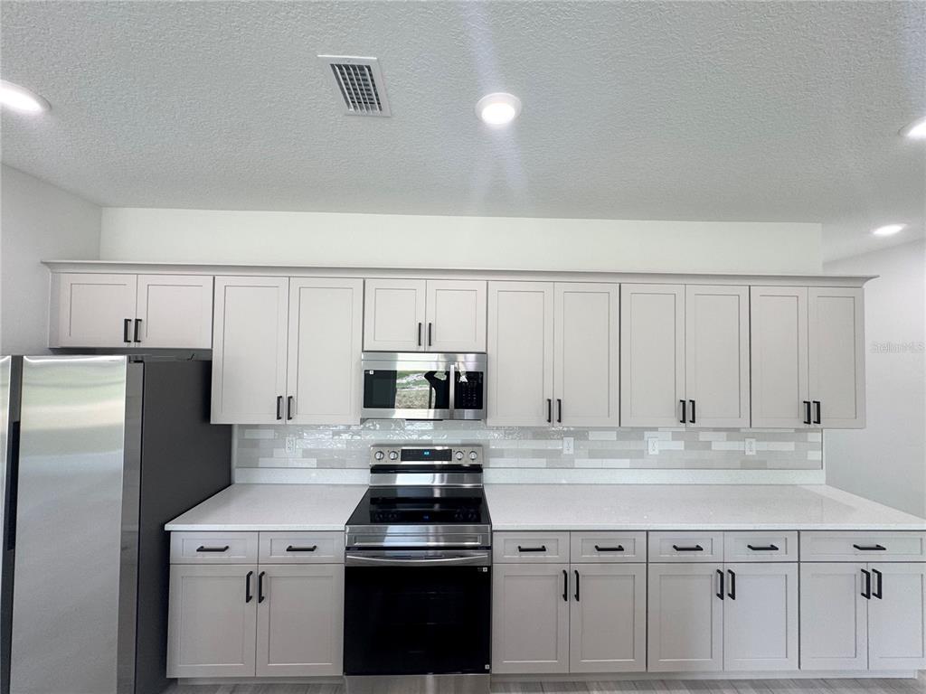 1690 Hamilton Avenue Southwest Palm Bay, FL 32908 - Photo 28 of 56 a kitchen with stainless steel appliances a sink stove refrigerator and cabinets