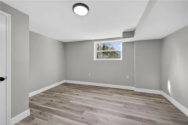 an empty room with wooden floor and window