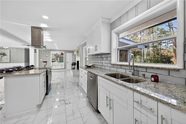 a kitchen with stainless steel appliances granite countertop a sink and white cabinets