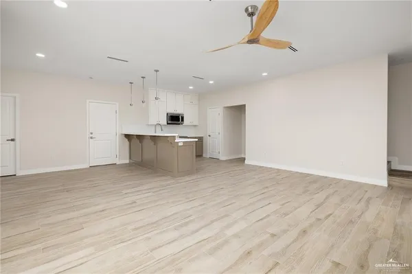 a view of kitchen and empty room with wooden floor