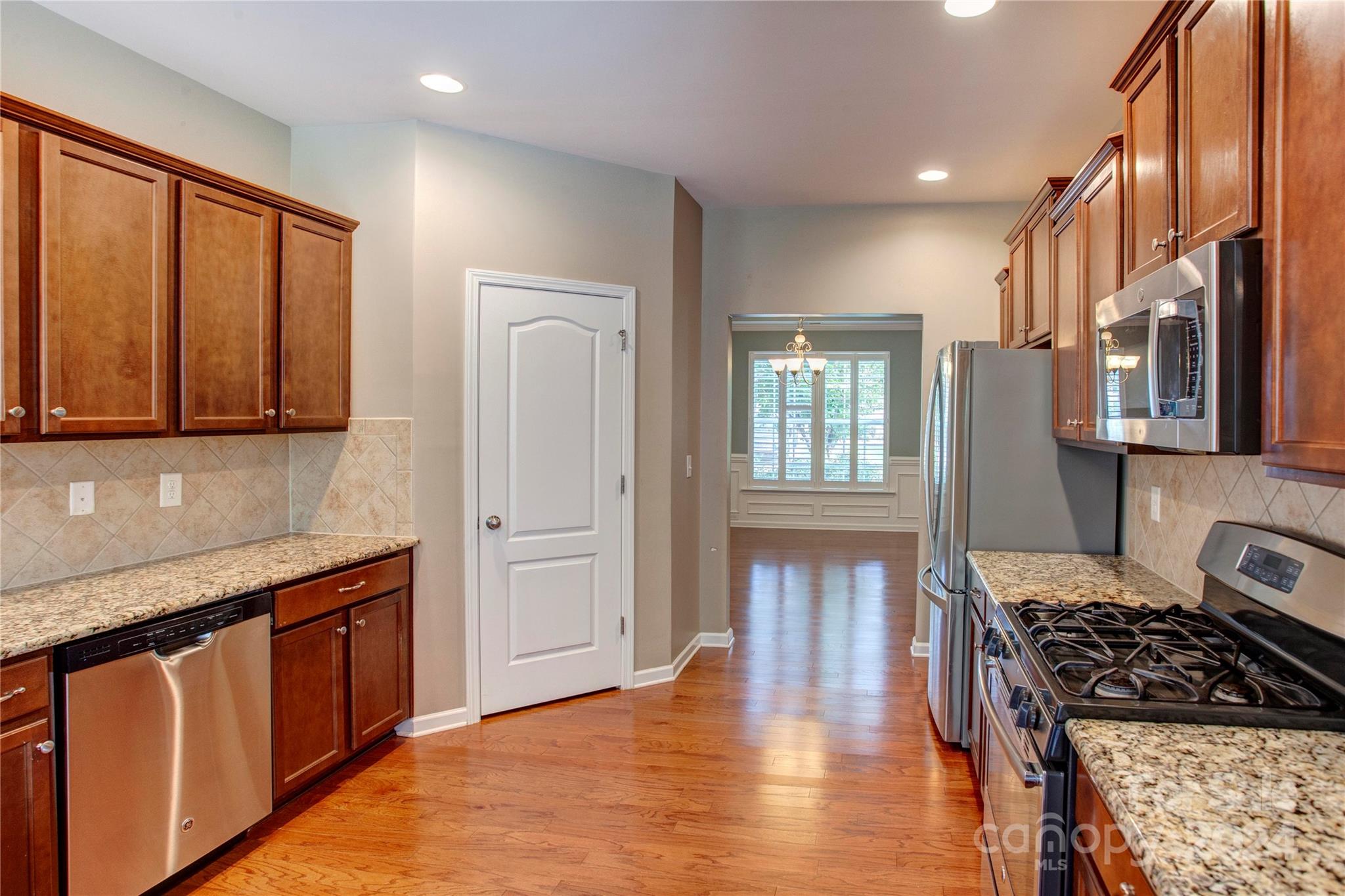 8899 Happiness Road Harrisburg, NC 28075 - Photo 7 of 30 a kitchen with stainless steel appliances granite countertop a stove top oven a sink dishwasher a refrigerator and cabinets with wooden floor