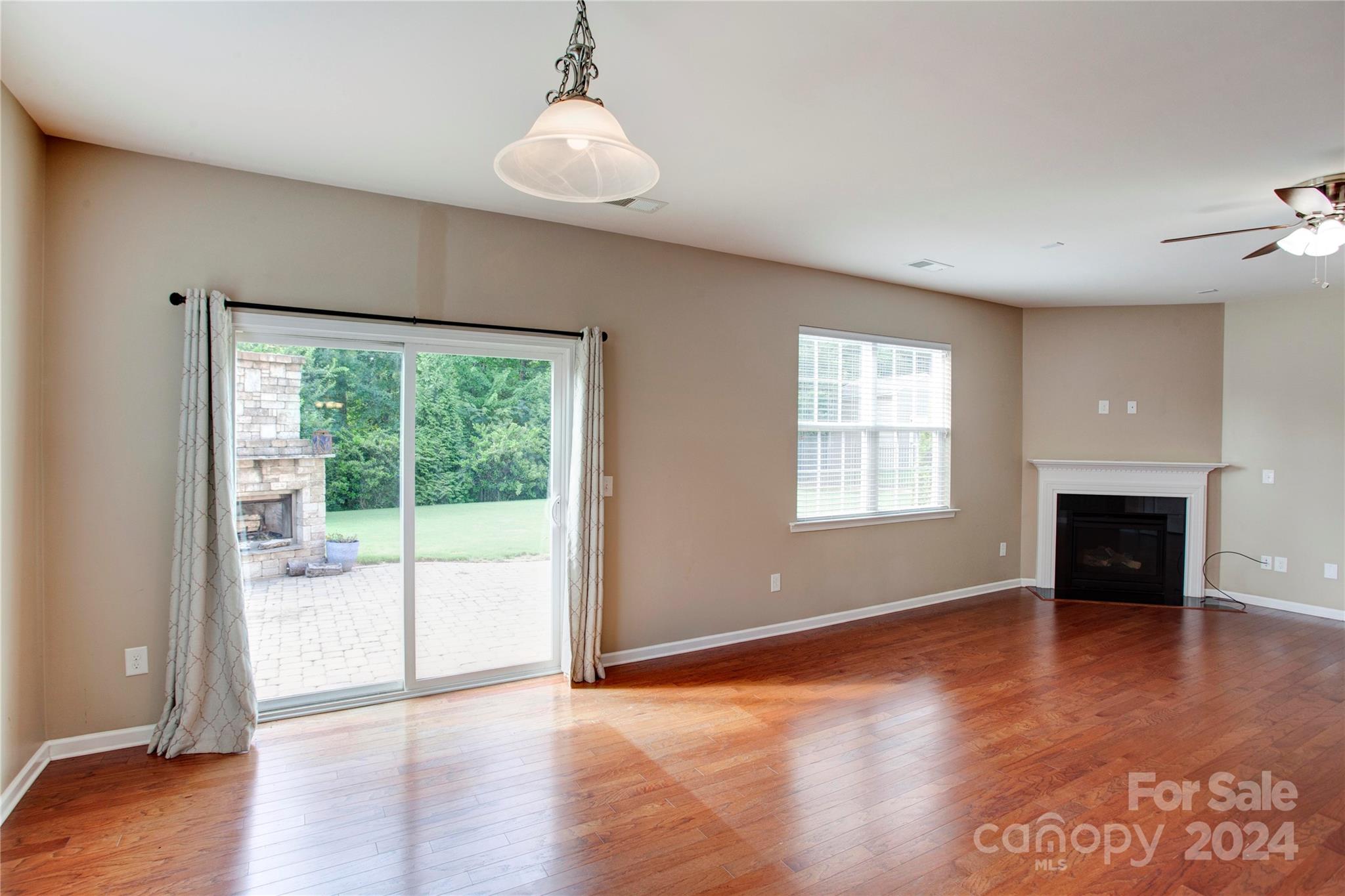 8899 Happiness Road Harrisburg, NC 28075 - Photo 9 of 30 an empty room with wooden floor fireplace and windows