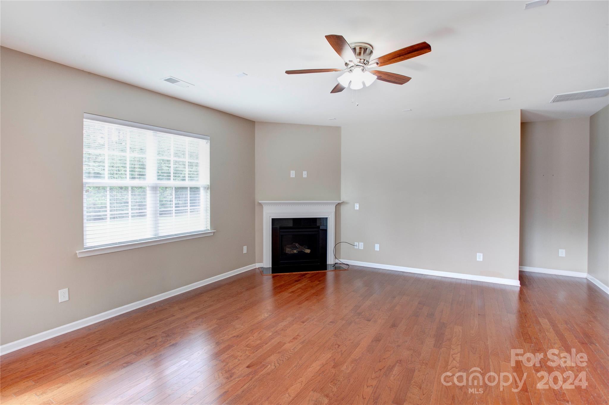 8899 Happiness Road Harrisburg, NC 28075 - Photo 10 of 30 an empty room with wooden floor a ceiling fan and a window