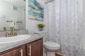 a bathroom with a granite countertop sink and a toilet