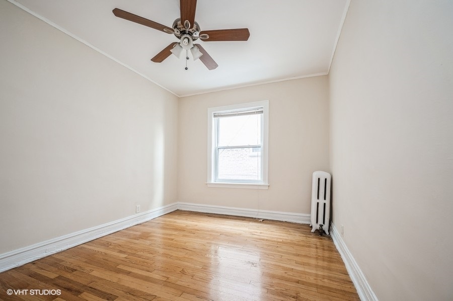 4817 North Springfield Avenue, Unit 1E Chicago, IL 60625 - Photo 5 of 6 an empty room with wooden floor fan and windows