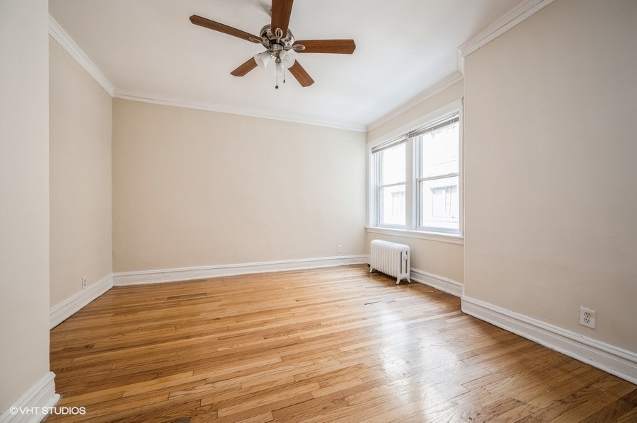 4817 North Springfield Avenue, Unit 1E Chicago, IL 60625 - Photo 6 of 6 an empty room with wooden floor fan and windows