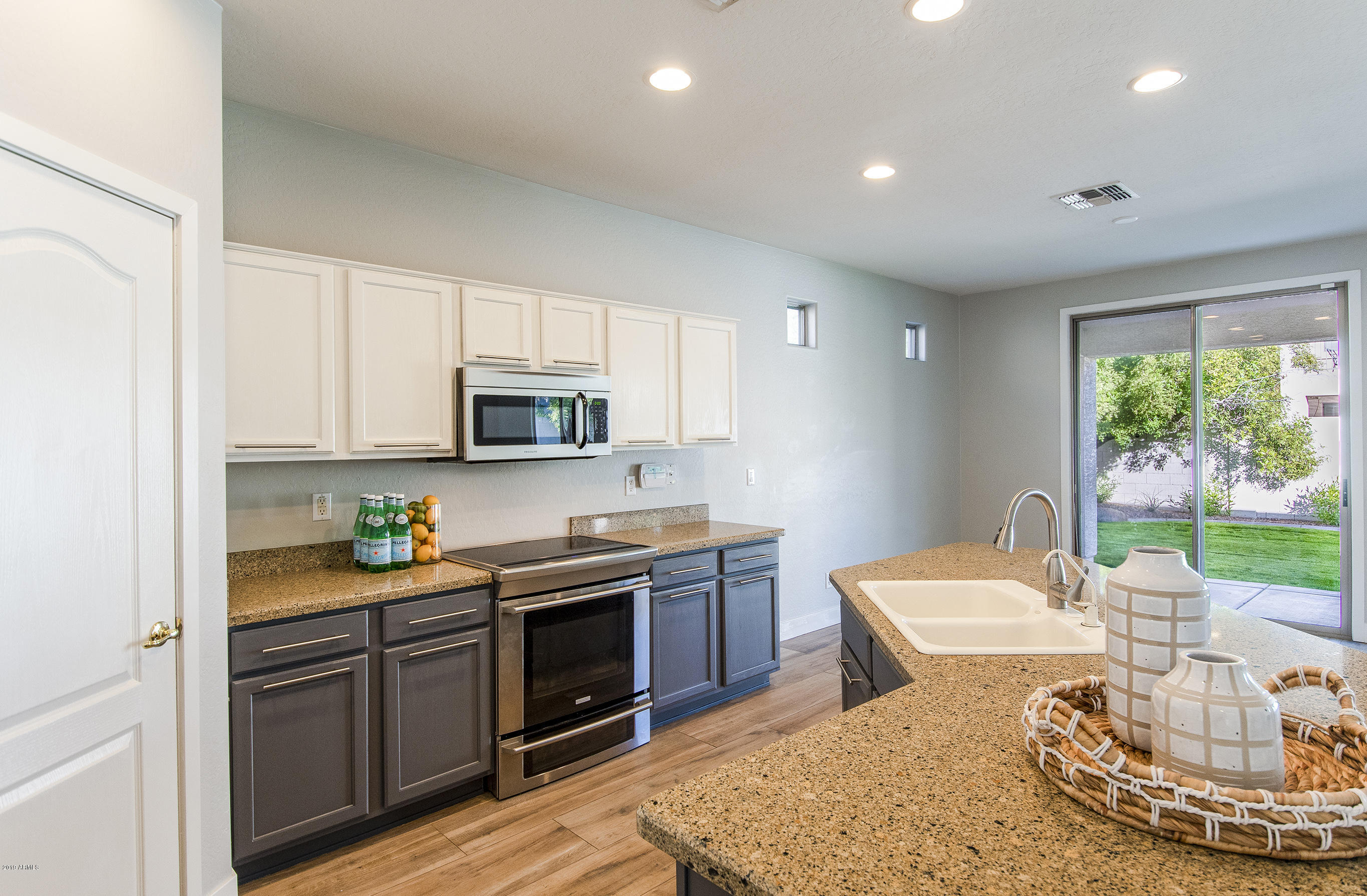 3236 East Phelps Street Gilbert, AZ 85295 - Photo 4 of 29 a kitchen with stainless steel appliances granite countertop a stove a sink a microwave a dining table and chairs