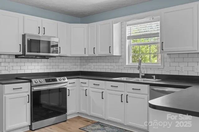 a kitchen with stainless steel appliances granite countertop a stove a sink dishwasher and a refrigerator with wooden floor