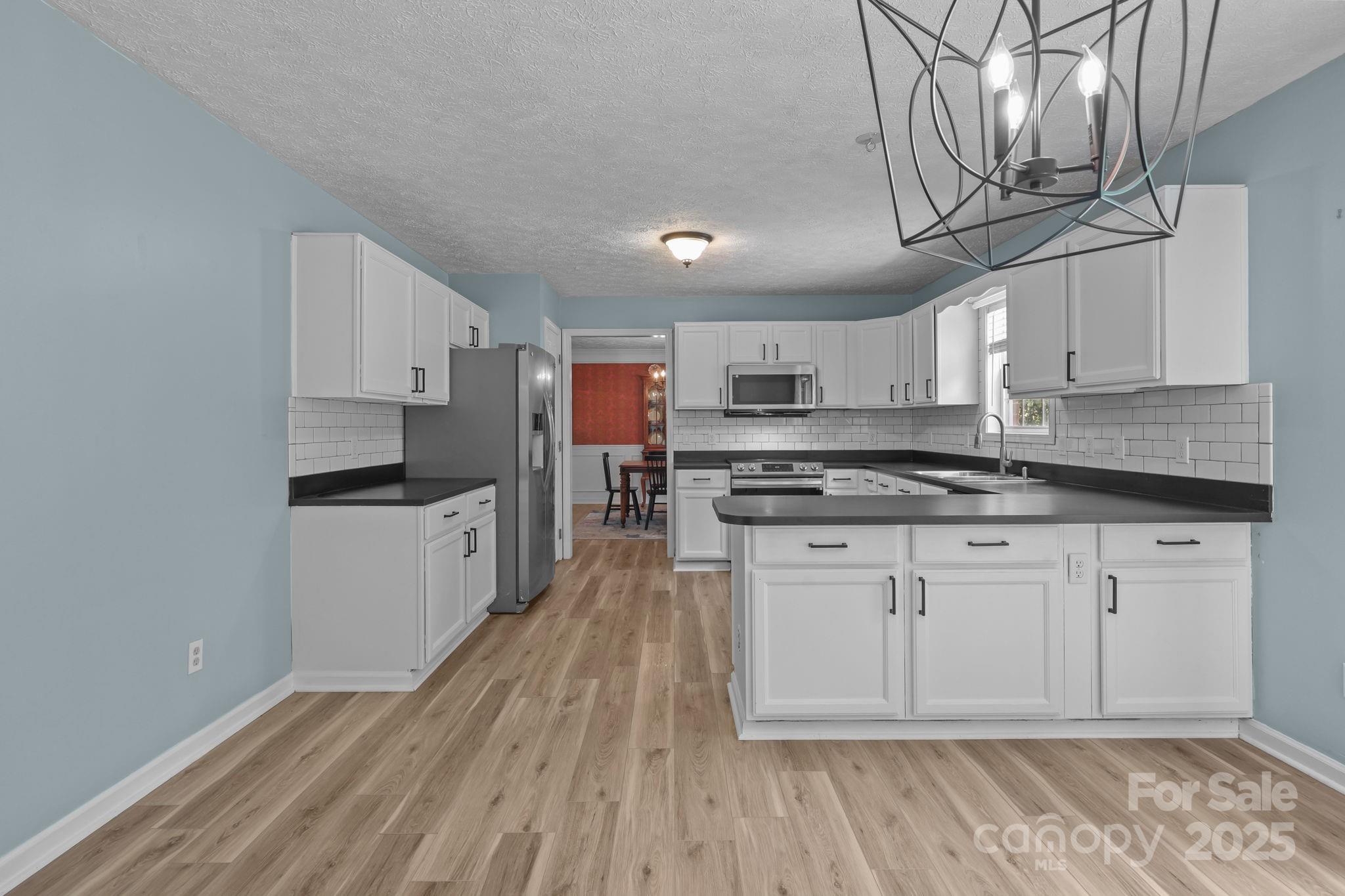 25611 Bridgeport Road Albemarle, NC 28001 - Photo 17 of 47 a kitchen with stainless steel appliances granite countertop a stove a sink dishwasher and a refrigerator with wooden floor