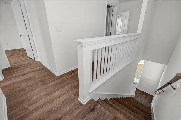 a view of a hallway with wooden floor and staircase