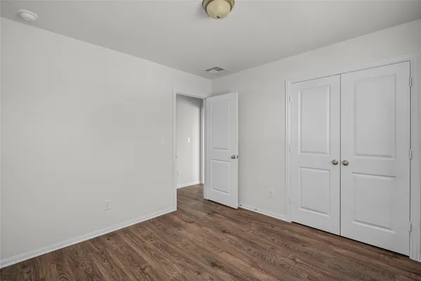 a view of an empty room with wooden floor and closet