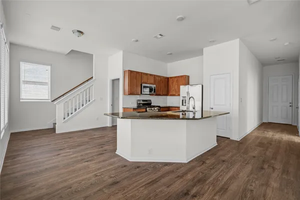 a kitchen with granite countertop a refrigerator and a stove top oven