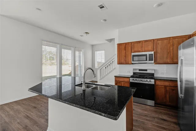 a kitchen with granite countertop a refrigerator stove and sink