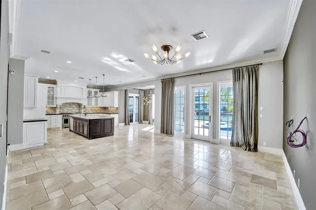 a view of an empty room with glass door and chandelier fan