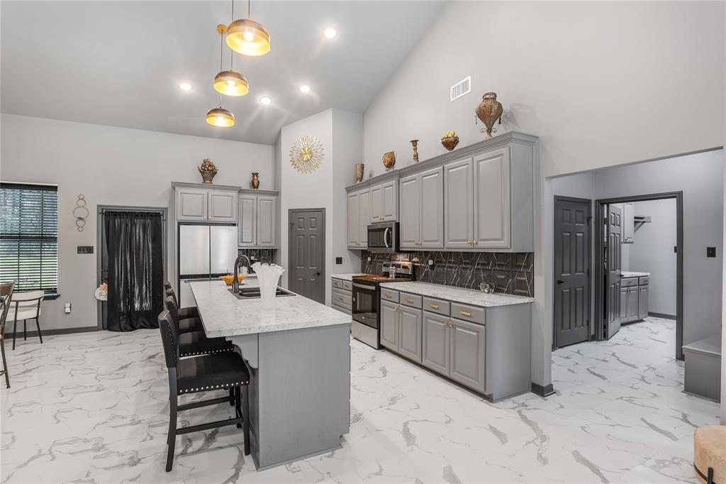 1373 George Ephram Cord 166 Road Overton, TX 75684 - Photo 12 of 40 Vaulted ceiling kitchen featuring an island with a breakfast bar, stainless steel appliances, abundant cabinetry, and patterned tile flooring